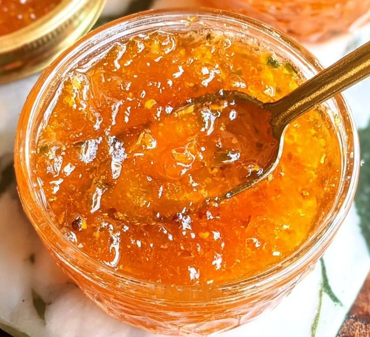 Jar of homemade Peach Jalapeno Jam with fresh peaches and jalapenos